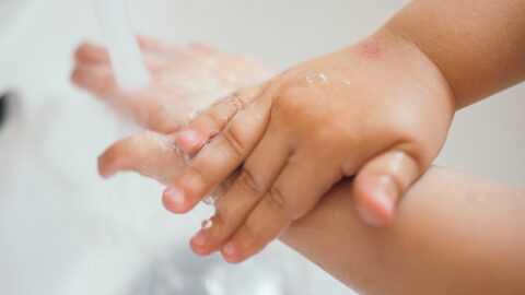 A child washing her hands with soap under a tap