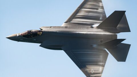 An F-35C stealth fighter in flight trailing vapour