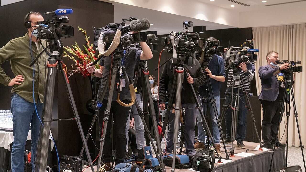 A speaker at a press conference behind a row of microphones