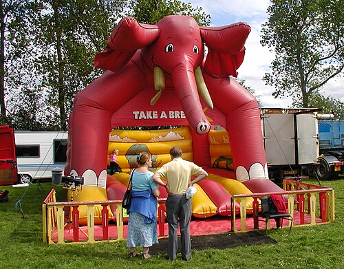 A red inflatable bouncy castle with an elephant design at an outdoor event